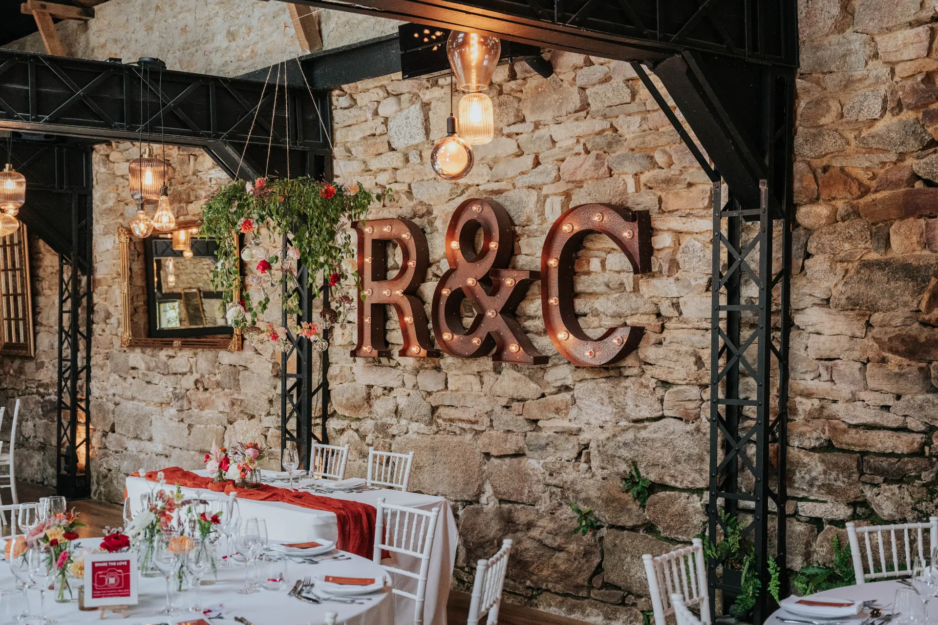 Tables de mariage dressées dans une grange en pierre avec lettres lumineuses R & C — traiteur mariage à Pont-l'Abbé, Pays Bigouden