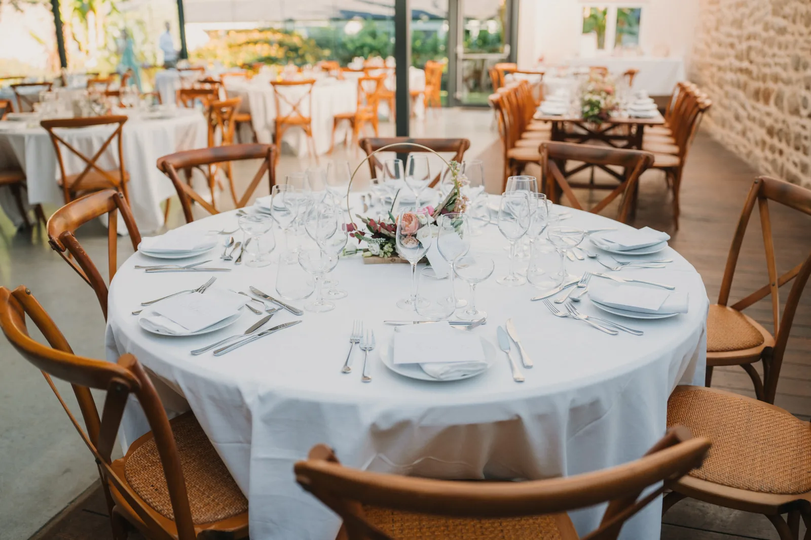Table ronde de mariage dressée (nappage blanc, verrerie et centre de table fleuri) au Domaine de Kerenez à Loctudy — réception assurée par Les Temps Gourmands, traiteur mariage à Pont-l'Abbé en Pays Bigouden (Finistère)